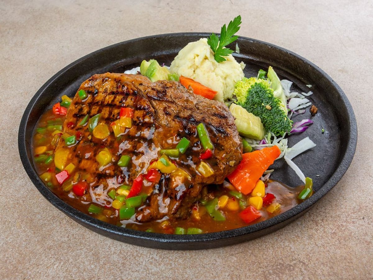 ستيك الشيف الخاص — ستيك مشوي طري مع صلصة سي إن بي الحمراء المميزة، مع أناناس حلو وذرة. مزيج متناغم من النكهات المالحة والحلوة | Cock "N" Bull, Sharjah